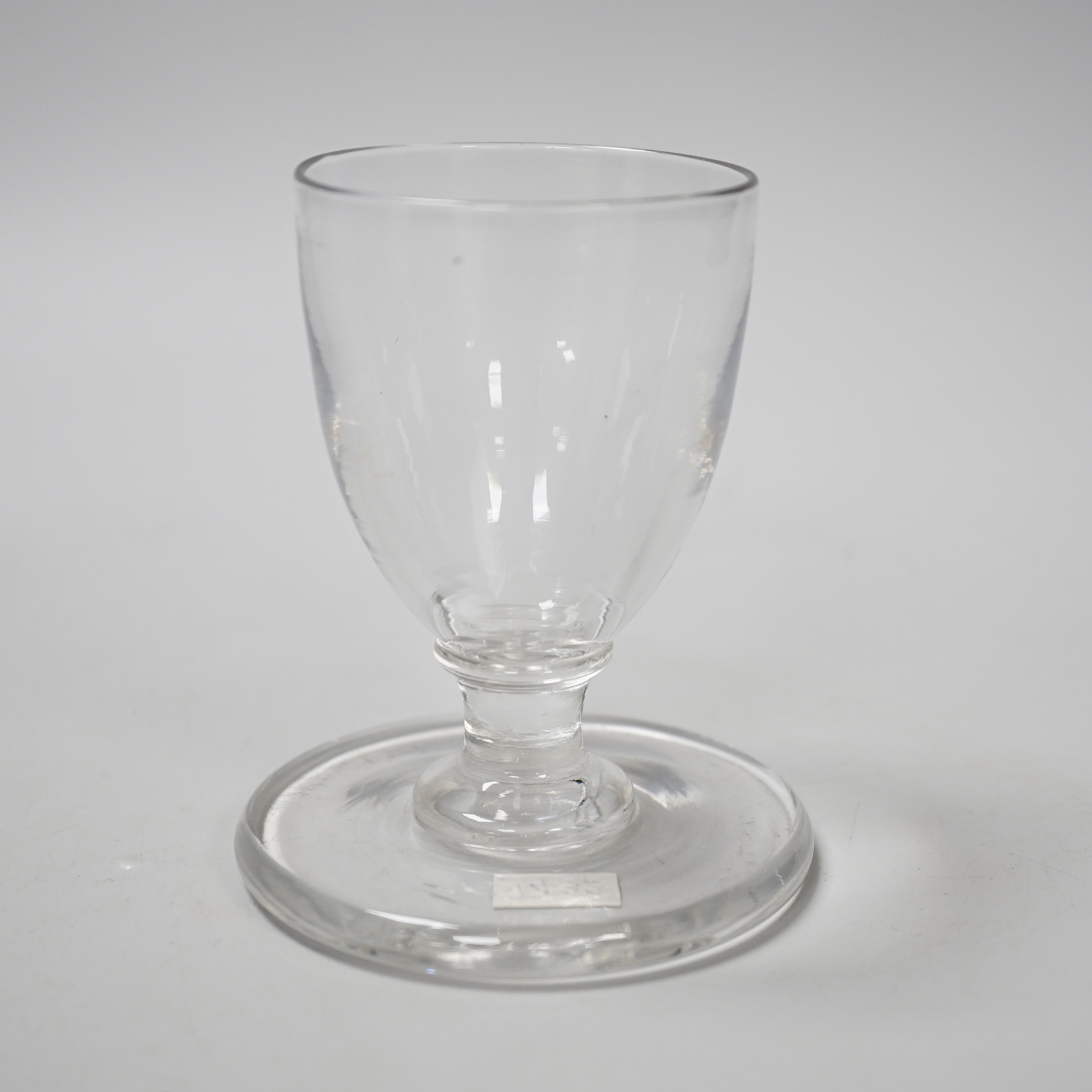 An English lead crystal ships’ dram, c1790-1800, the bowl, which is heavily striated, is of rounded funnel form on a capstan stem, with a very wide and heavy firing foot, 9.9cm high